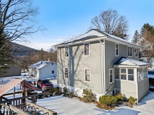 view of snowy exterior featuring a sunroom