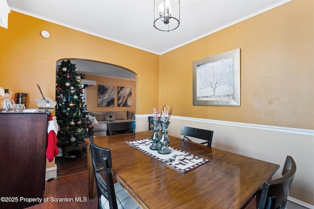 dining room with crown molding, dark wood-type flooring, and a chandelier