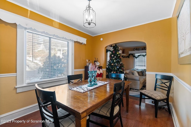 dining area featuring crown molding, dark hardwood / wood-style flooring, and a notable chandelier