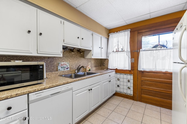 kitchen featuring sink, tasteful backsplash, light tile patterned floors, white appliances, and white cabinets