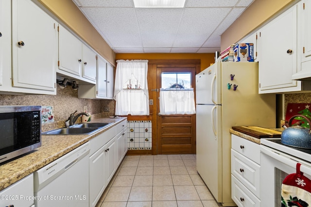 kitchen with white cabinetry, sink, a drop ceiling, and white appliances