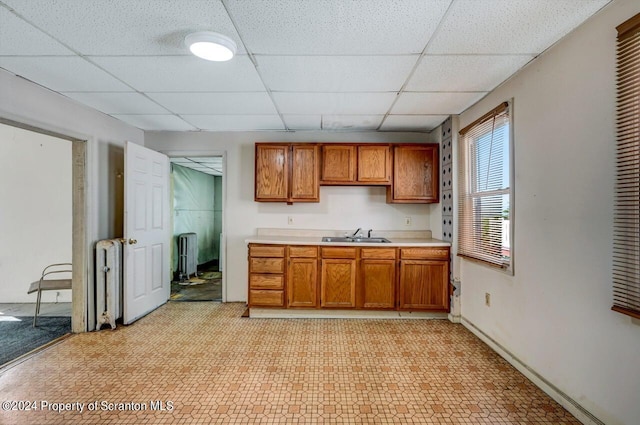 kitchen featuring a paneled ceiling, radiator heating unit, and sink