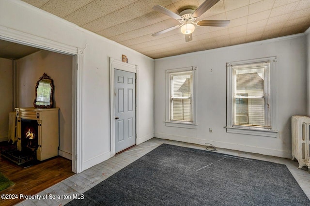 interior space featuring dark hardwood / wood-style flooring, ceiling fan, radiator heating unit, and ornamental molding