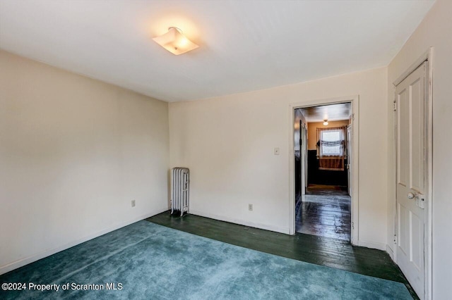 empty room with dark wood-type flooring and radiator