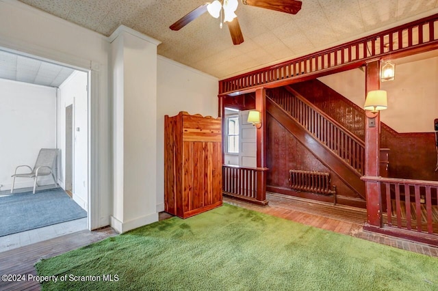 unfurnished living room featuring carpet flooring, ceiling fan, and radiator