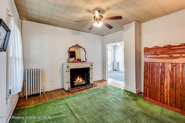 unfurnished living room featuring radiator heating unit, ceiling fan, ornamental molding, and hardwood / wood-style floors