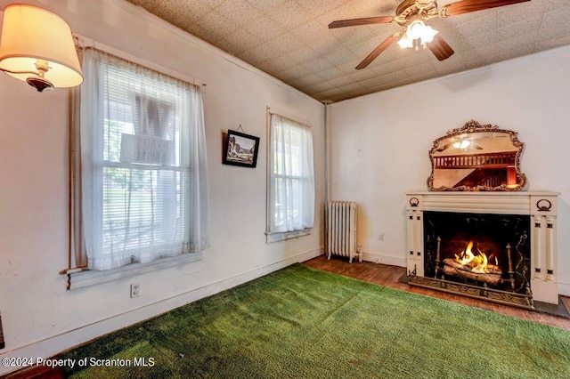 interior space featuring ceiling fan, dark hardwood / wood-style floors, radiator heating unit, and ornamental molding