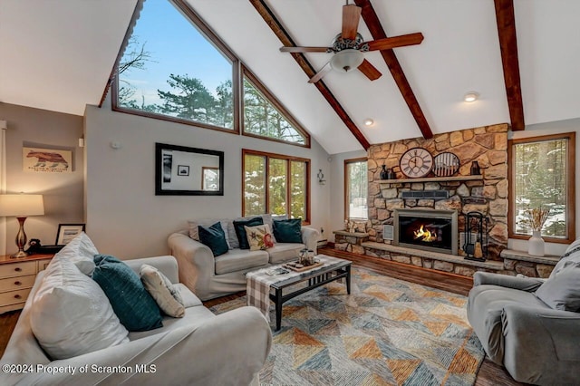 living room with beam ceiling, ceiling fan, a stone fireplace, high vaulted ceiling, and hardwood / wood-style flooring