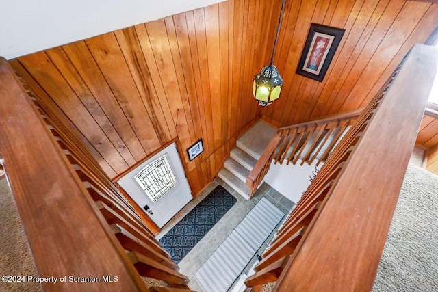 staircase with wood walls and carpet floors