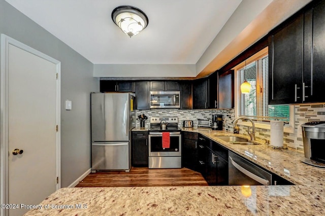 kitchen with light stone countertops, sink, dark wood-type flooring, tasteful backsplash, and appliances with stainless steel finishes