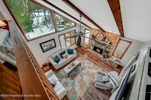 living room featuring hardwood / wood-style floors, high vaulted ceiling, a stone fireplace, ceiling fan, and beamed ceiling