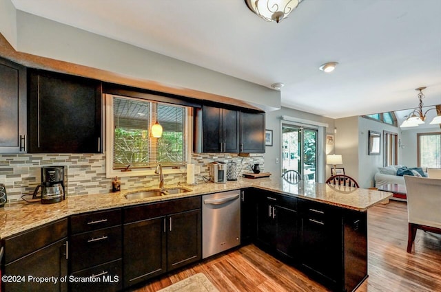 kitchen featuring pendant lighting, sink, stainless steel dishwasher, tasteful backsplash, and kitchen peninsula