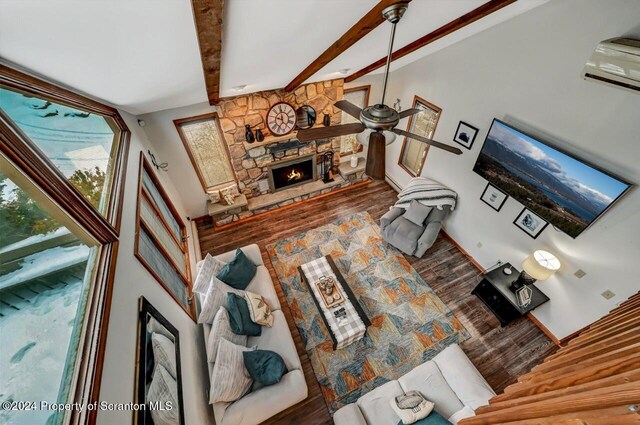 living room featuring a fireplace, ceiling fan, wood-type flooring, beamed ceiling, and a high ceiling