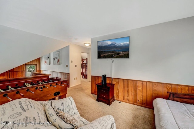 interior space featuring light carpet, lofted ceiling, and wooden walls