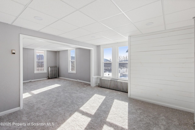 carpeted empty room with radiator heating unit and a paneled ceiling