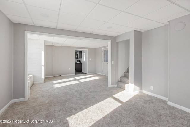 basement with a paneled ceiling and light colored carpet