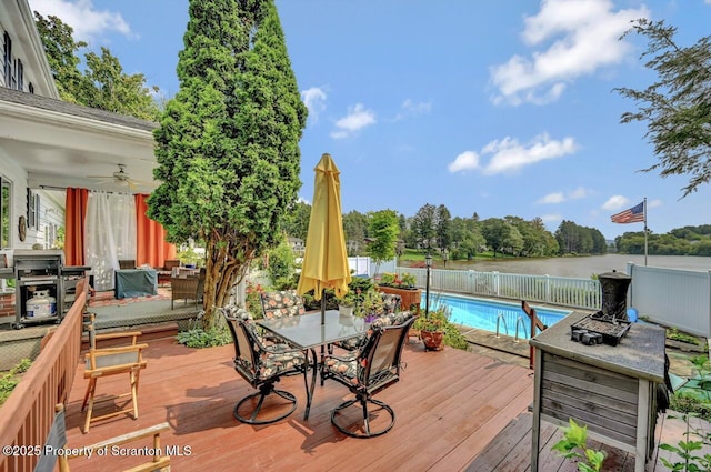 7 Lakeside Dr, Clarks Summit, PA 18411 - deck with outdoor dining space, a ceiling fan, a fenced backyard, and a water view