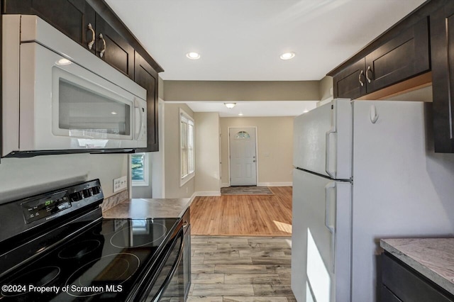 kitchen featuring dark brown cabinetry, light hardwood / wood-style floors, and white appliances