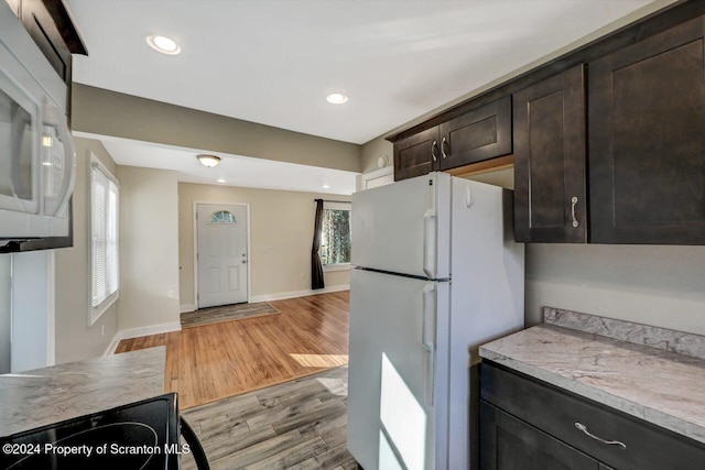 kitchen with light wood-type flooring, white appliances, and dark brown cabinetry