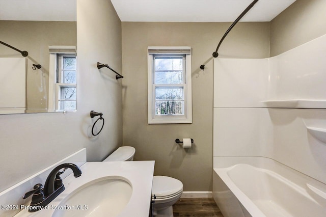 full bathroom with hardwood / wood-style flooring, toilet, tub / shower combination, and sink