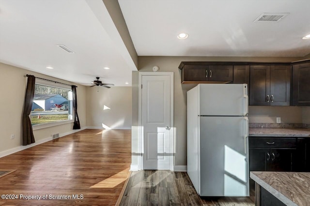 kitchen featuring ceiling fan, dark brown cabinets, white fridge, and dark wood-type flooring