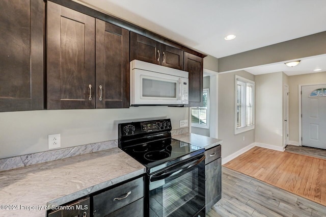 kitchen with dark brown cabinetry, light hardwood / wood-style flooring, and black / electric stove