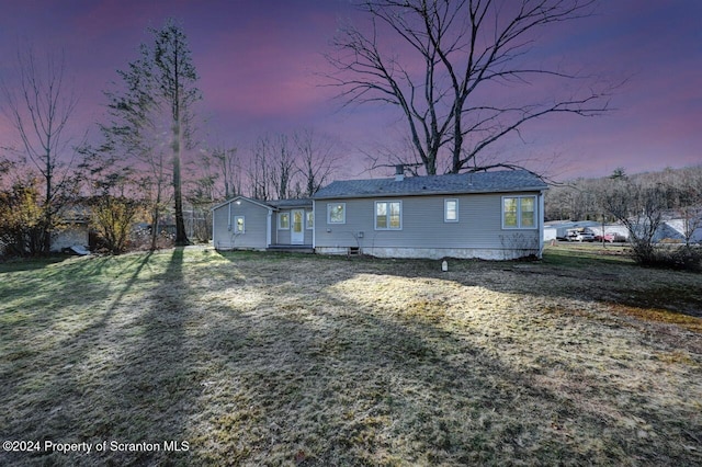 back house at dusk featuring a yard