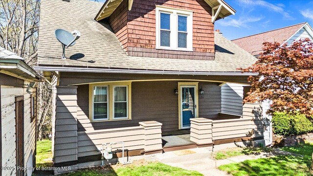 exterior space with a porch and roof with shingles