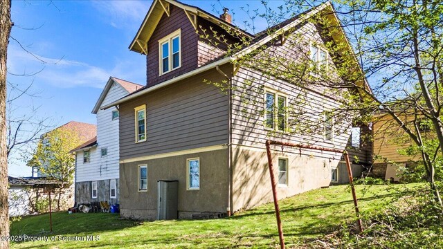 rear view of house featuring a chimney and a yard