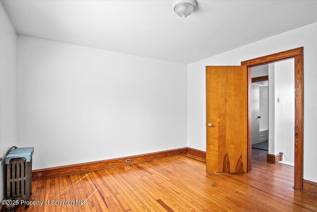unfurnished room with radiator heating unit, baseboards, and hardwood / wood-style floors