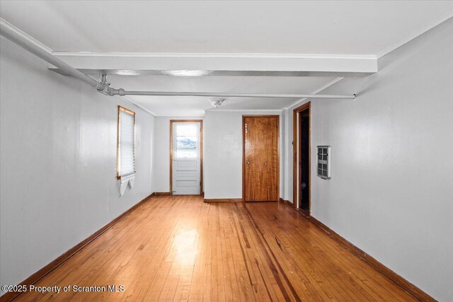 spare room with crown molding, baseboards, and light wood-style floors