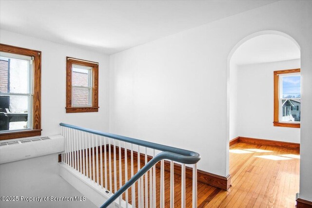 interior space featuring arched walkways, baseboards, and wood-type flooring