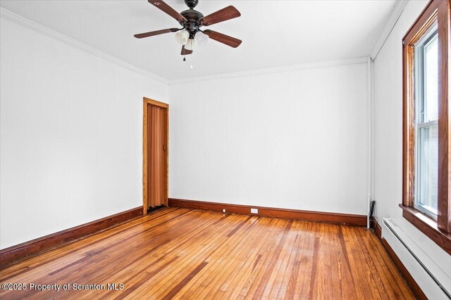 spare room featuring a ceiling fan, ornamental molding, baseboards, hardwood / wood-style flooring, and a baseboard radiator