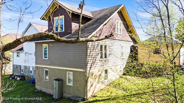 view of home's exterior with roof with shingles and a yard