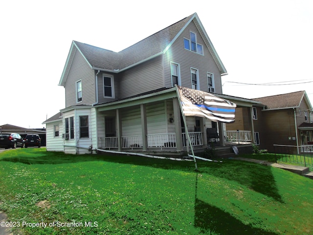 back of house featuring a lawn and covered porch