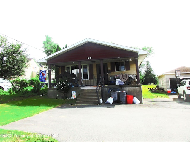 bungalow-style home with a carport, a porch, and a front lawn