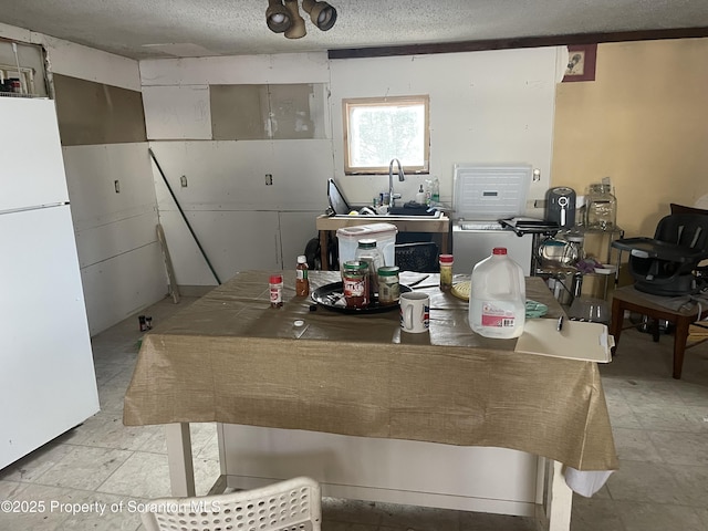 kitchen featuring a textured ceiling and freestanding refrigerator