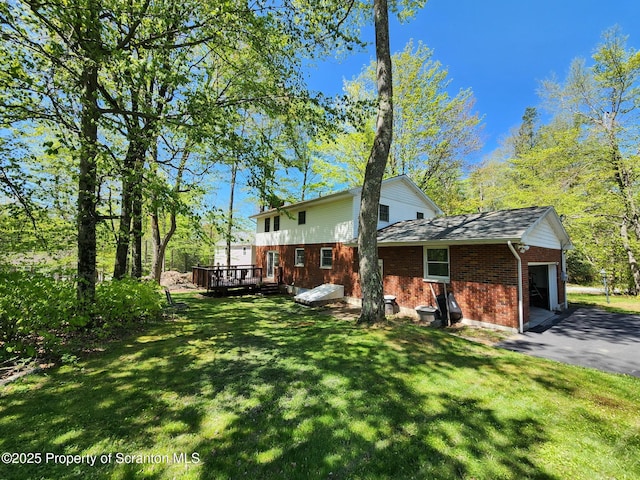 410 Lake Spangenberg Rd, Jefferson Twp, PA 18436 - rear view of property featuring brick siding, an attached garage, a wooden deck, a lawn, and driveway