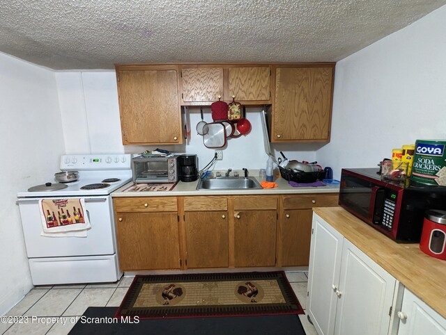121 Sand St, Dunmore, PA 18510 - kitchen with white electric range oven, black microwave, light countertops, a textured ceiling, and light tile patterned floors