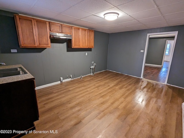 121 Sand St, Dunmore, PA 18510 - kitchen with under cabinet range hood, light wood-style flooring, brown cabinetry, a paneled ceiling, and light countertops