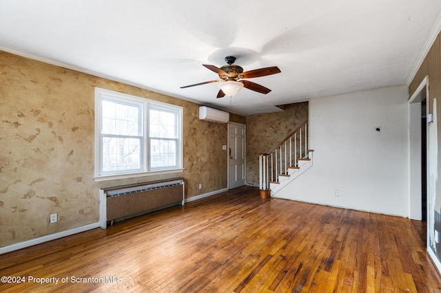 interior space featuring radiator, ceiling fan, a wall mounted AC, crown molding, and wood-type flooring