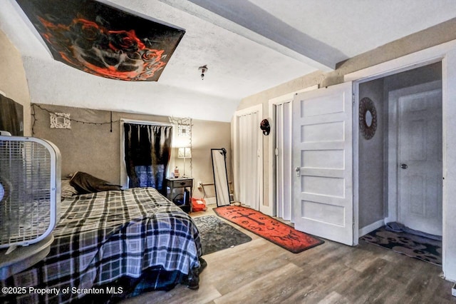 bedroom with beam ceiling and hardwood / wood-style floors