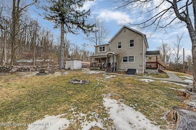 rear view of property with a shed, an outdoor fire pit, and a lawn