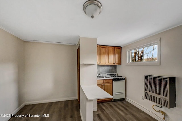 kitchen featuring white gas range oven, heating unit, sink, backsplash, and dark wood-type flooring