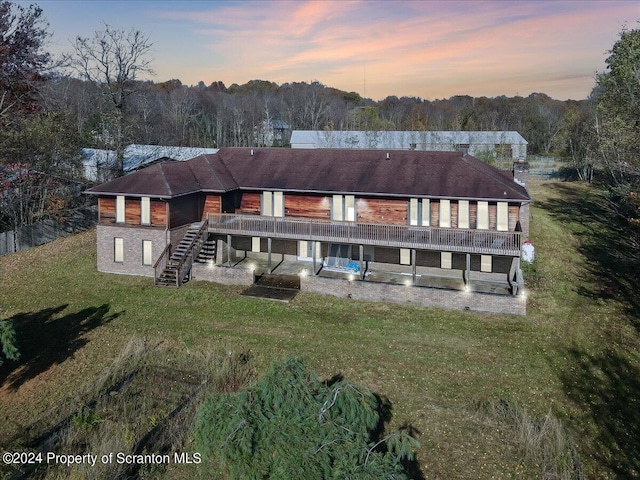 back house at dusk with a lawn and a patio area