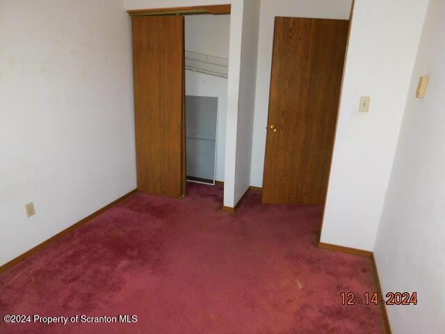 unfurnished bedroom featuring dark colored carpet and a closet