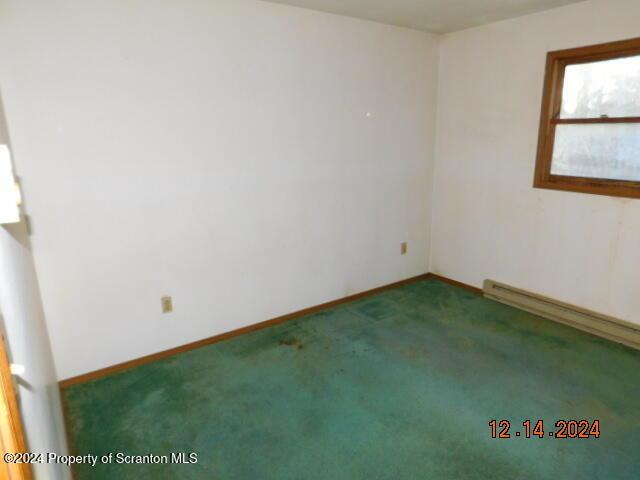 unfurnished room with dark carpet and baseboard heating