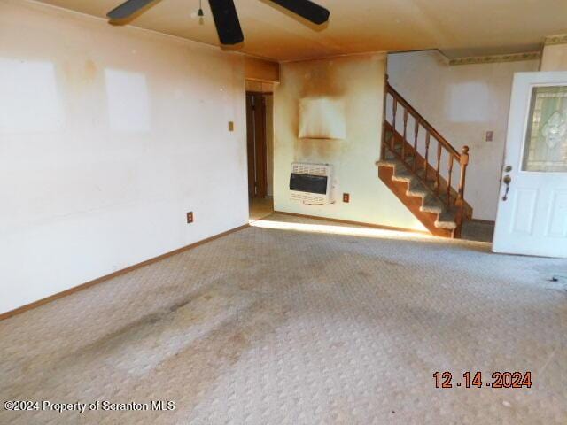 unfurnished living room with carpet flooring, heating unit, ceiling fan, and a fireplace