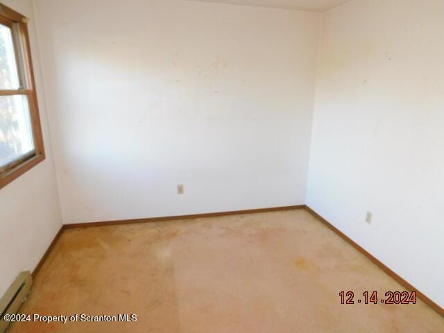 empty room featuring carpet floors and baseboard heating