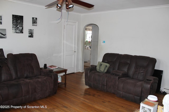 living room featuring arched walkways, crown molding, a ceiling fan, and wood finished floors